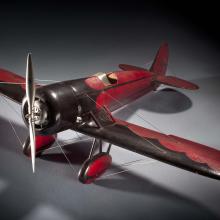 Red and brown-colored monoplane model with one engine.