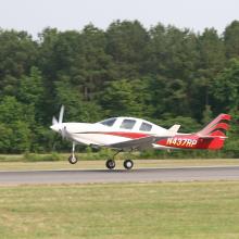 Side view of white and red monoplane with one engine. Monoplane is in takeoff position. Registration number "N437RP" painted in white near tail of plane.