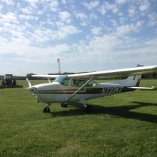 Side view of white and brown monoplane with one engine. Registration number "N77KZ" painted in white near the rear of the fuselage.