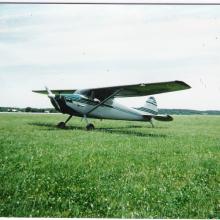 Side view of white and green monoplane with one engine.