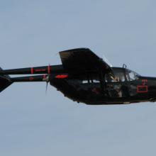 Side view of black, twin engine monoplane with engines placed on the back of the wings. Monoplane is in flight.