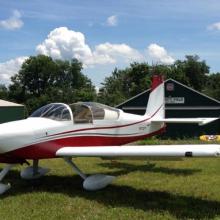 Front view of white and red-colored monoplane with single engine and fixed landing gear.