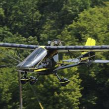 Side view of a black monoplane in flight. Monoplane has fixed landing gear.