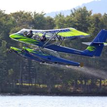 Side view of blue and green seaplane with pontoon floats below fuselage.