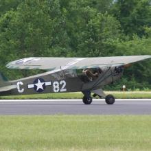 Side view of gray and green military monoplane with one engine.The letter "C" and number "82" are painted in white paint on the sides of a blue and white star emblem.