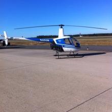 Side view of white and blue helicopter with two propellors at the top. Registration number "N4013R" painted in white on front of tail.