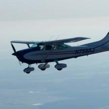 Side view of white monoplane in flight. Monoplane has single engine and fixed landing gear.