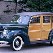 Side view of dark-colored metal, four-door automobile with wooden sides.