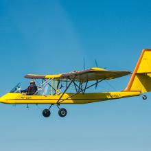 Side view of yellow and red biplane in flight.