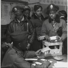 A group of Tuskegee Airmen, who were African-American male pilots during World War II, work on putting escape kits together.