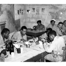 Joe Louis, an African-American boxer, dines with African-American Tuskegee Airmen.