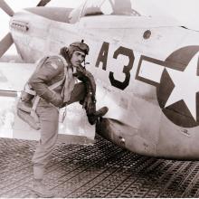 Lt. Edward M. Thomas, an African-American Tuskegee Airman, sits on the wing of an aircraft.