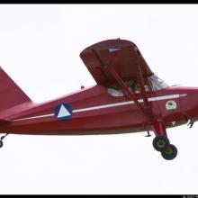 Side view of red monoplane with one engine. Registration number "N26265" is painted in white on the rudder.