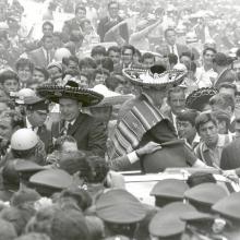 The three Apollo 11 astronauts (Neil Armstrong, Edwin "Buzz" Aldrin, Jr., and Michael Collins) are wearing sombreros and ponchos. They are surrounded by thousands of people in Mexico City, Mexico.