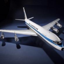 Plastic, white and blue commercial aircraft model with four engines attached to the sides of the plane. Aircraft has white and light blue Pan American World Airways livery.