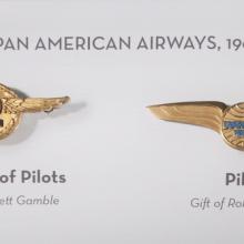 Set of two badges given to the captain of pilots, on the left, and a pilot, on the right, of Pan American Airways in the 1960s. The badges both are gold-colored and have a circle shape surrounded by stylized wings.