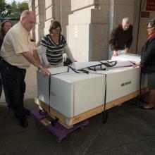 Five Museum staff members transport Neil Armstrong's spacesuit outside into another Smithsonian museum building.