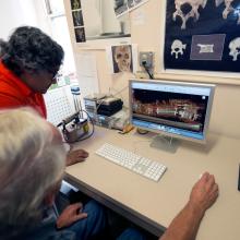 Two Museum staff members look at a CT scan of Neil Armstrong's spacesuit on a desktop computer.