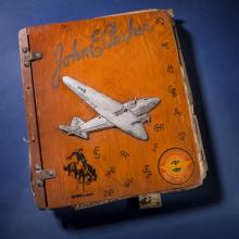 Wooden-colored scrapbook cover featuring a white aircraft. The scrapbook owner's name is written in cursive above the aircraft.