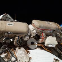 Two Russian Cosmonauts, both wearing spacesuits, work outside of the International Space Station during a spacewalk.