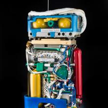 Cutaway view of life support system, a large set of wires and tubes attached to multiple cylinders, and oxygen purge system, which features multiple smaller cylinders around a green tube.