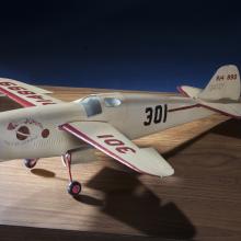 Side view of white monoplane model with one engine. The number 301 is painted in black on the rear of the fuselage and in red on the left wing.