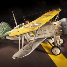 Side view of tan brown and yellow biplane model aircraft with one engine. 