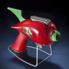 Side view of red-colored steel gun toy with light green trigger.