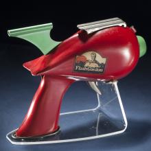 Side view of red-colored steel gun toy with light green trigger. Flash Gordon logo on the middle of the toy.