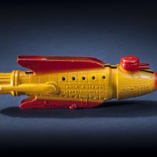 Side view of yellow rocket with red fins and nose.