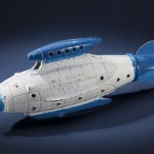 Side view of white torpedo-shaped destroyer toy with blue propellor, nose, and fins.