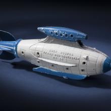 Side view of white torpedo-shaped destroyer toy with blue propellor, nose, and fins.