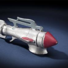 Side view of silver-colored metal missile-shaped spaceship with red nose.