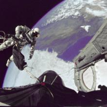 Edward White, a male astronaut, performs a spacewalk while tethered to the Gemini 4 spacecraft.