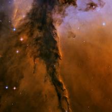 A nebula of dust and gases with orange and light purple colours.