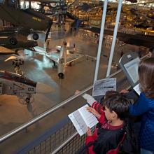 Three younger Museum guests observe objects in the Museum while playing a Museum-sanctioned alternate reality game.