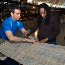 A Museum staff member assists two Museum visitors with activities at a table during an open house event.