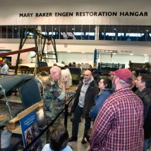 Museum specialists give a presentation to visitors inside the Museum's restoration hangar.