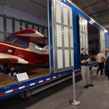 A Museum staff member provides visitors a lesson on artifact transport in front of a partially open storage unit.