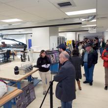 A member of the Museum's conservation staff presents work they have done to conserve objects to many visitors inside the Museum's conservation laboratory.