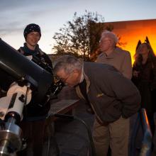 Museum staff assist in allowing visitors to use telescopes at a Museum event.