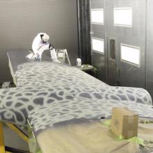 A museum specialist uses white paint to recreate the original pattern of paint on an aircraft during its restoration process.