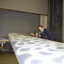 A Museum specialist and a Museum curator discuss the finished paint job on a silver-colored aircraft undergoing the restoration process.