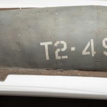 A gray-colored engine cover belonging to a gray military aircraft. The engine cover features the marking "T2-490" on the right side of the visible cover.