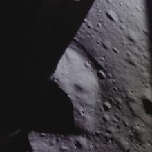 Partial view of the Moon's surface taken from a camera mounted on the Lunar Module. The surface features multiple craters.