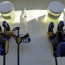 A pair of tool sets used to perform resin consolidation experiments. The tools include a syringe, a jar of a yellow transparent object, and a large blue, black, and yellow object.