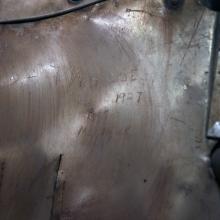 Signatures from engineers and guards etched onto a portion of a silver monoplane. 