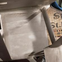 Close-up view of a side of the section below the cockpit of the Spirit of St. Louis, a silver-colored monoplane.