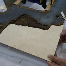 A Museum staff member holds a thin layer of plywood to be used on holes in a World War II era aircraft.