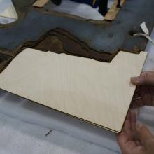 A Museum staff member places a second layer of plywood intended for use in repairing holes in a World War II era aircraft.